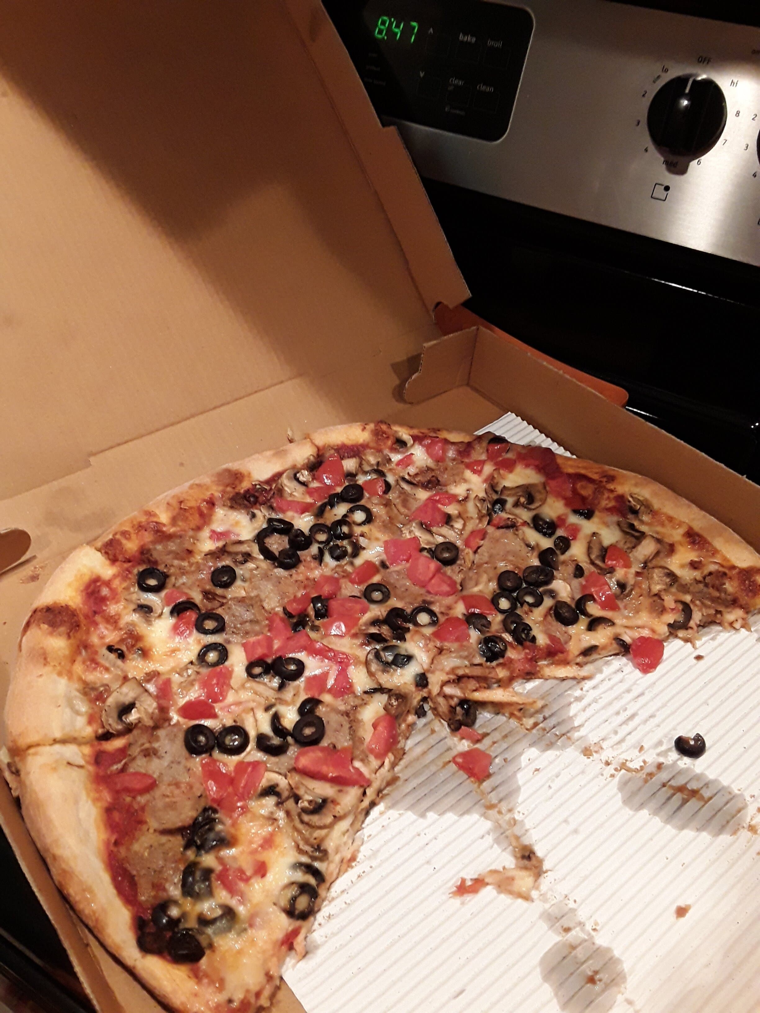 Hand-tossed San Remo pizza with olives, tomato and sausage, fresh out of the box